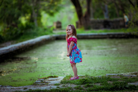 在绿藻丛生的湖边玩耍的女孩
