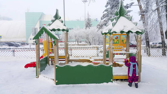 操场上积满了雪。冬天，一个孩子在街上玩耍