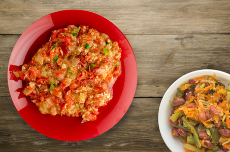 Stewed tomatoes with onions in a plate on a wooden background 