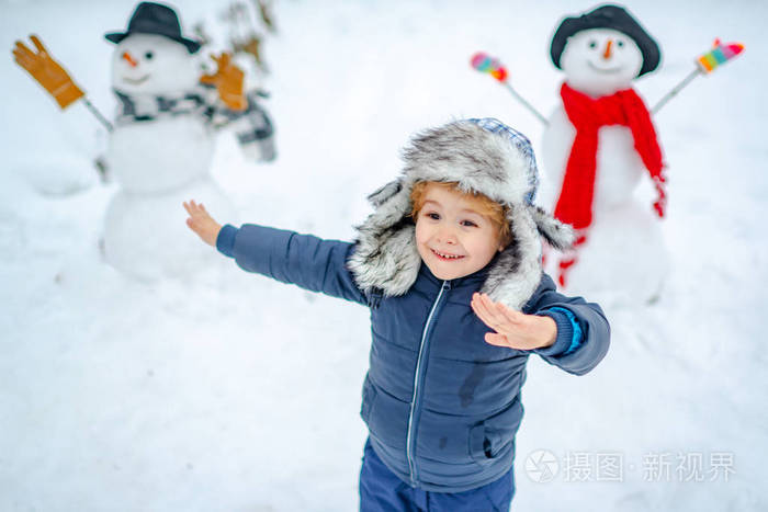 孩子在雪地上玩雪人。快乐的孩子在冬季公园和雪人玩。冬天的孩子。雪地里的孩子们。