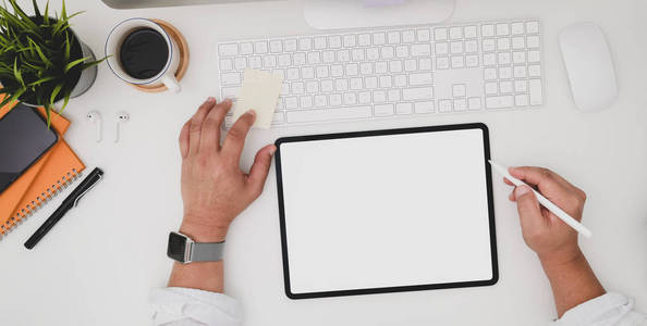 Top view of young businessman writing on blank screen tablet in 