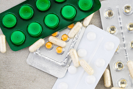  Stethoscope, pills, tablets and capsules on a gray background .