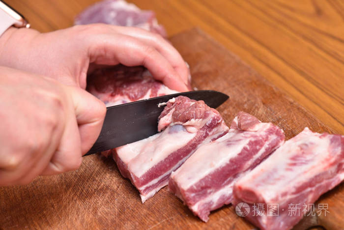 用黑色的小刀切肉特写放在砧板上猪排