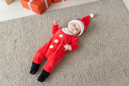 美丽的小宝宝庆祝圣诞节。新年假期。婴儿穿着圣诞服装，戴着圣诞帽，俯视图