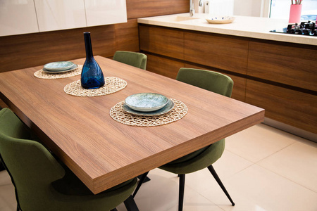 现代厨房，木胡桃木餐桌和绿色椅子