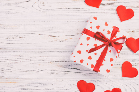 情人节或其他节日手工礼品纸红心和节日包装礼品盒。礼品盒放在白色木质桌面上，带复制空间，设计用空白空间