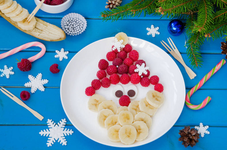 用覆盆子香蕉和巧克力做成的圣诞老人脸。圣诞节和新年的搞笑食物主意。美味健康的水果甜点。
