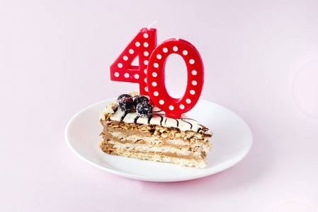 周年美味一块美味的蛋糕,上面有数字4和0的红色蜡烛,白色盘子上有40岁