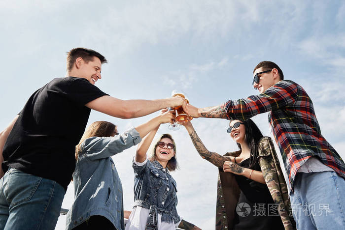 一群朋友节前在屋顶上的露天酒吧喝啤酒举杯欢笑