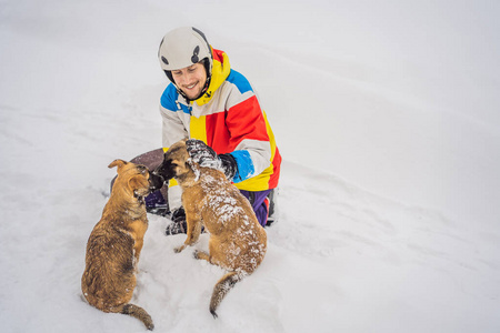 冬天，年轻的男性滑雪板手在滑雪场和小狗玩耍