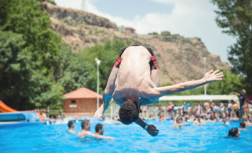 一个男人跳进一个有蓝色水的池子里。