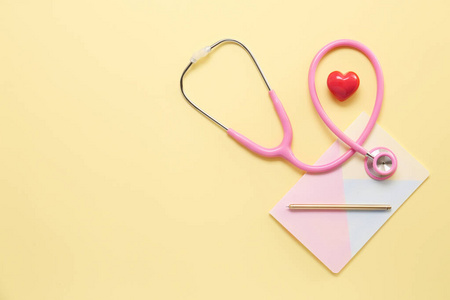 听诊器，心脏和笔记本的彩色背景。心脏病学概念