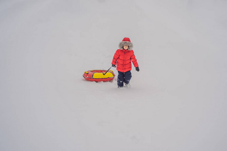 孩子在雪管上玩得很开心。那个男孩正在骑管子。儿童冬季娱乐