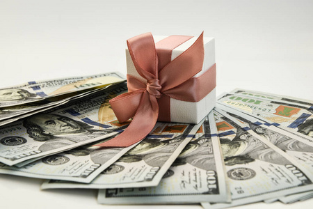 以美元为背景，粉红色丝带的白色礼品盒