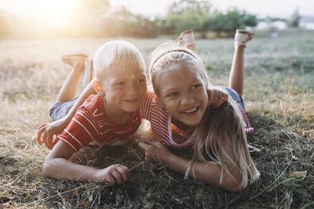两个金发碧眼的孩子，兄妹在草地上拥抱