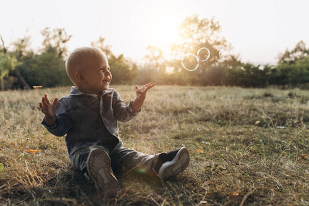 a kid playing in the nature with bubbles with amazing smile 