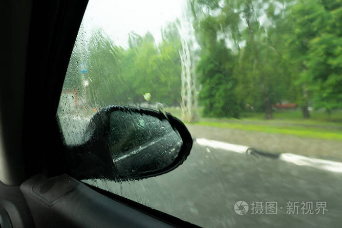 雨中透过车窗看到的景色.汽车挡风玻璃雨刷在雨中开着.