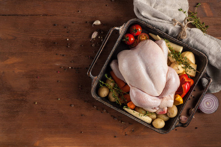 Uncooked whole chicken with vegetables ready for baking. 