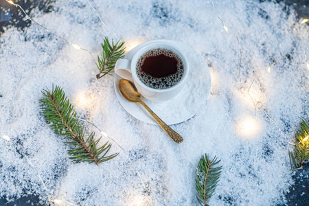 白杯子加热咖啡。站在人造雪里。在云杉树枝附近。新年和圣诞节。