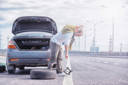 Replacing the wheel of a car on the road. A man doing tire work 