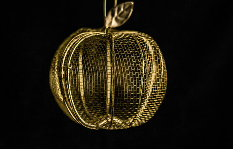 黑色背景上的金苹果形状的茶壶图片
