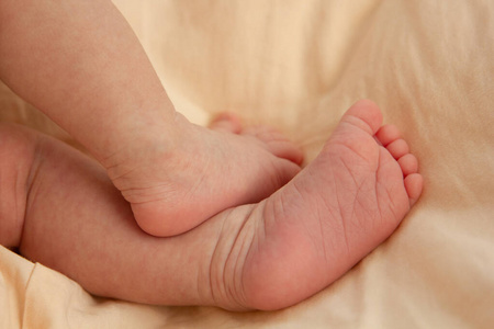一个新生婴儿可爱的小脚丫踩在桃色格子布上.新生儿照片