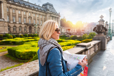 比利时布鲁塞尔，一名妇女在皇宫背景下阅读城市地图