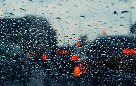 透过雨滴看到城市道路的挡风玻璃。