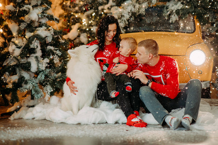 一家人坐在圣诞树背景下的狗旁边