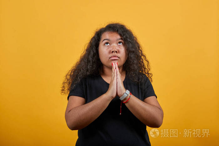 严肃的超重妇女双手合十祈祷抬头