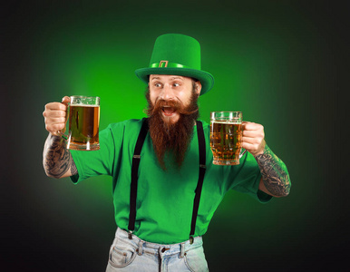 一个留着胡子的男人，在黑暗的背景下喝着啤酒。圣帕特里克节庆典