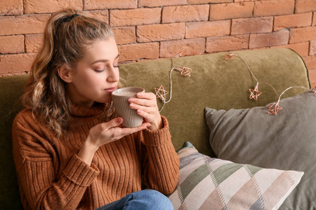 穿冬装的年轻女子在家喝热巧克力