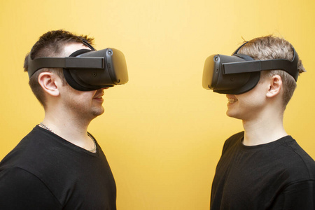 两个戴着VR眼镜的家伙在黄色背景上玩射击游戏，朋友游戏玩家的对手在虚拟现实眼镜里打架