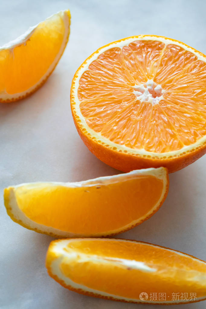 close-up half of orange and slice on light table surface. fresh