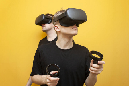 两个玩家两个戴着vr眼镜的家伙在黄色背景下玩射击游戏,朋友们,戴着