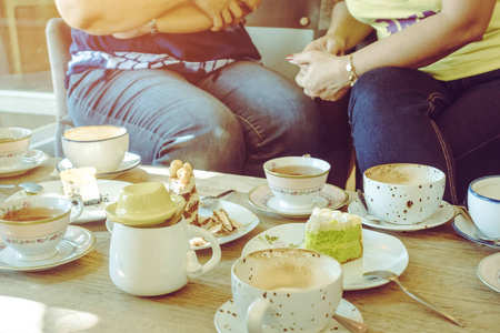 喝茶休闲快乐的女性朋友们下午在咖啡厅聚会,一起喝茶或喝咖啡,吃蛋糕