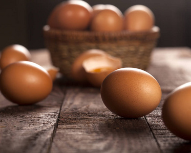 篮子里的棕色鸡蛋和乡村餐桌上的蛋黄碎鸡蛋。