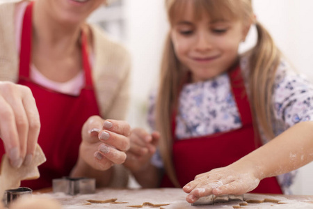 Cute little girl cutting gingerbread cookies from the stretched 