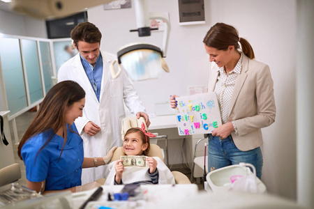 Child at dentist hold greenback for luck  