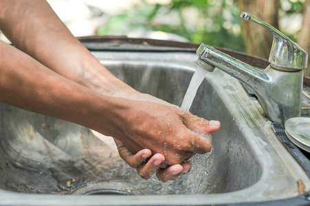 在公园里用水龙头洗手的人照片