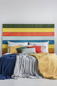有枕头毯子和彩虹色木材床头的彩色床