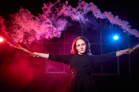 烟筒一个十几岁的胖女孩,手里拿着彩色烟筒,在夜间用彩色烟雾和黑色