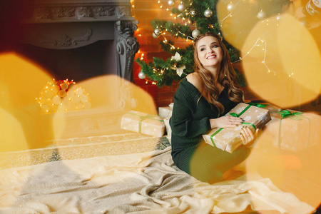 Elegant young lady sitting near Christmas tree