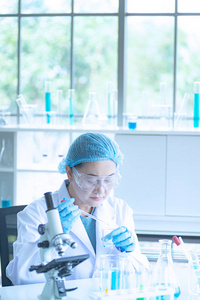 亚洲女科学家研究员技术员或学生利用显微镜进行研究或实验，显微镜是医学化学或生物实验室的科学设备