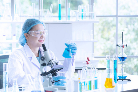 亚洲女科学家研究员技术员或学生利用显微镜进行研究或实验，显微镜是医学化学或生物实验室的科学设备