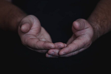 低调，一个忠实成熟的男人双手合十祈祷，双手交叉，手指交叉在一起敬拜上帝。孤立的黑色背景。概念