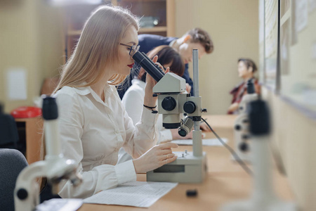 两个女孩和一个男孩用显微镜工作