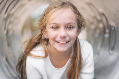 Pretty, little girl, having fun, lying on pipe on children playg