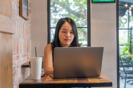 一个黑发女人在咖啡桌旁用笔记本电脑工作