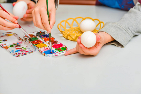 孩子们为复活节画彩蛋，一个男孩和一个女孩用小刷子画彩蛋。